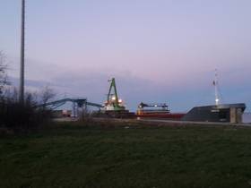 Abendliche Stimmung am Seehafen Ladebow, Kaikante - ein anliegendes Schiff wird per Förderband ent-/beladen
